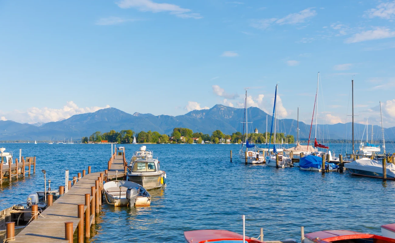 Boats at jetty at Seebruck with Fraueninsel at Lake Chiemsee, Bavaria on a sunny summer day