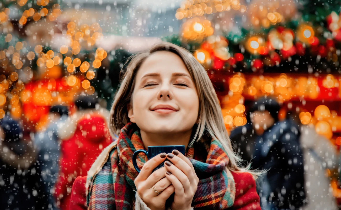 Beautiful adult girl with cup of hot drink at Christmas fair in Dresden, Germany