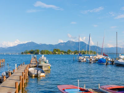 Boats at jetty at Seebruck with Fraueninsel at Lake Chiemsee, Bavaria on a sunny summer day