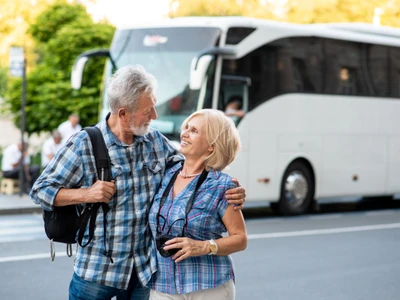 Happy senior couple of tourists hugging in front of tourist bus