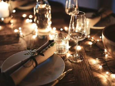 Closeup of a candlelit dining table set up with wineglasses and tableware for an evening dinner party